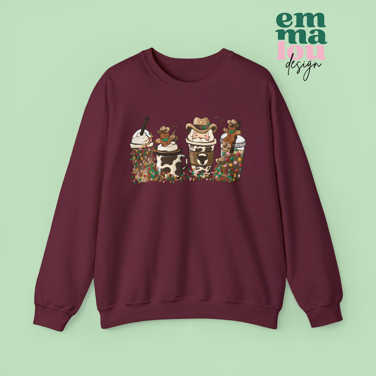 Maroon Sweatshirt featuring four western christmas coffee lattes. The graphic includes two cowboy gingerbread men and a westner Santa Claus with cow print coffee drins and christmas lights.