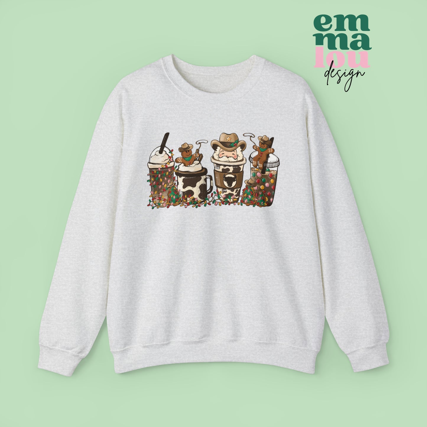 Ash Grey Sweatshirt featuring four western christmas coffee lattes. The graphic includes two cowboy gingerbread men and a westner Santa Claus with cow print coffee drins and christmas lights.