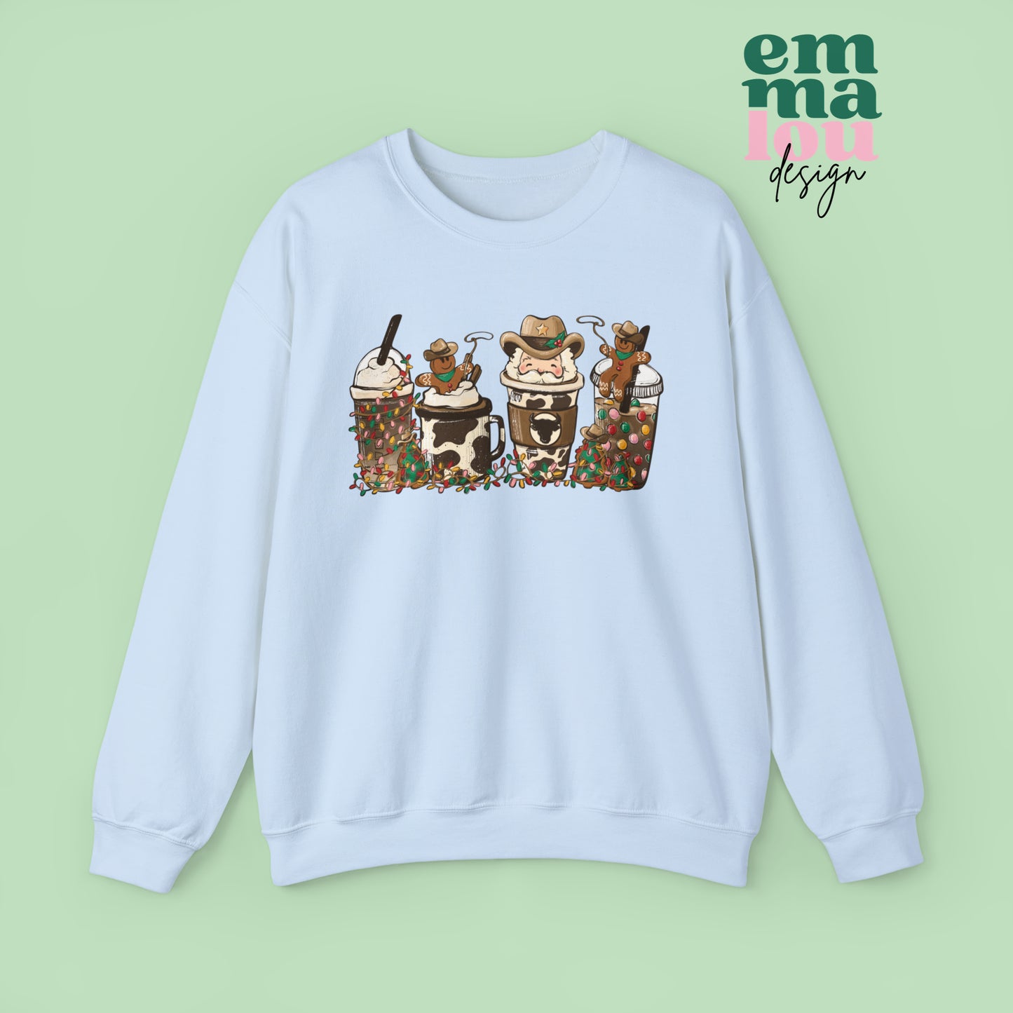 Light Blue Sweatshirt featuring four western christmas coffee lattes. The graphic includes two cowboy gingerbread men and a westner Santa Claus with cow print coffee drins and christmas lights.