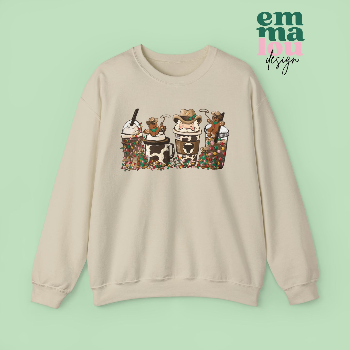 Sand Sweatshirt featuring four western christmas coffee lattes. The graphic includes two cowboy gingerbread men and a westner Santa Claus with cow print coffee drins and christmas lights.