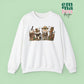 White  Sweatshirt featuring four western christmas coffee lattes. The graphic includes two cowboy gingerbread men and a westner Santa Claus with cow print coffee drins and christmas lights.